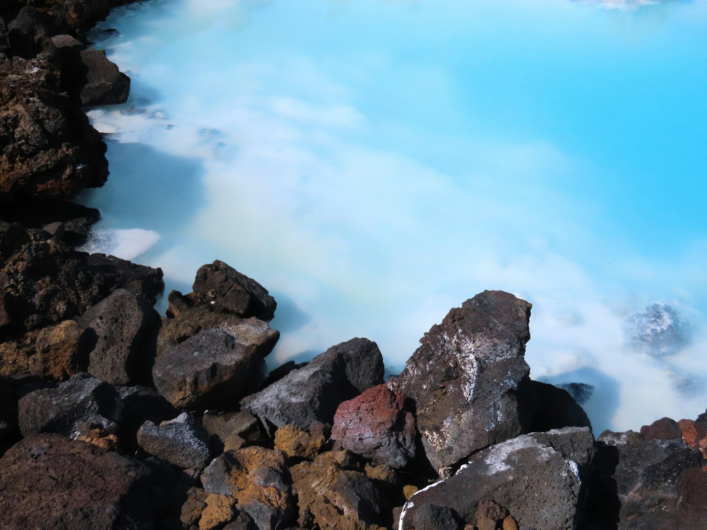 Milky blue lagoon meeting black lava rock